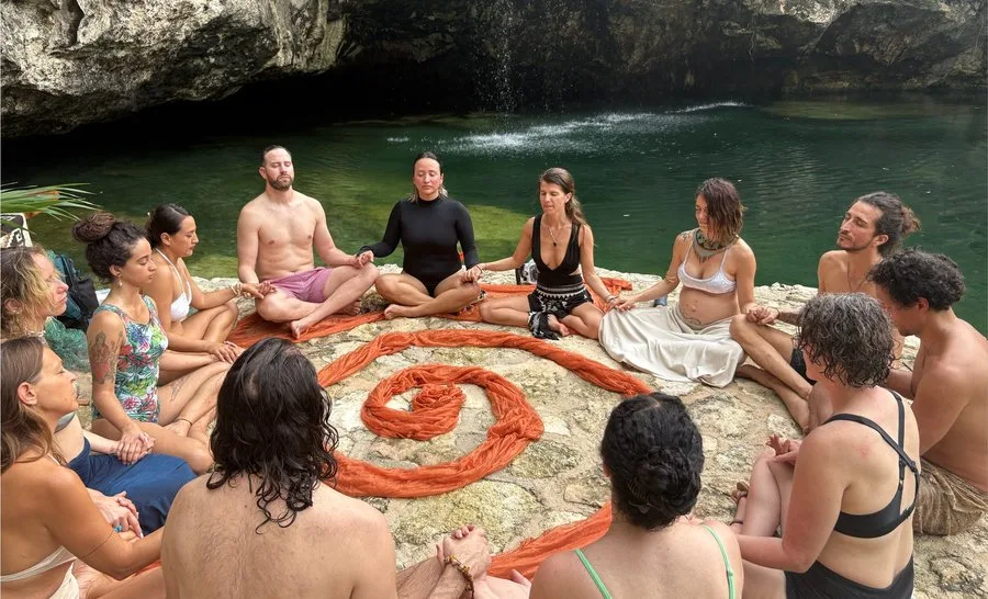 A circle of people meditating beside a cenote