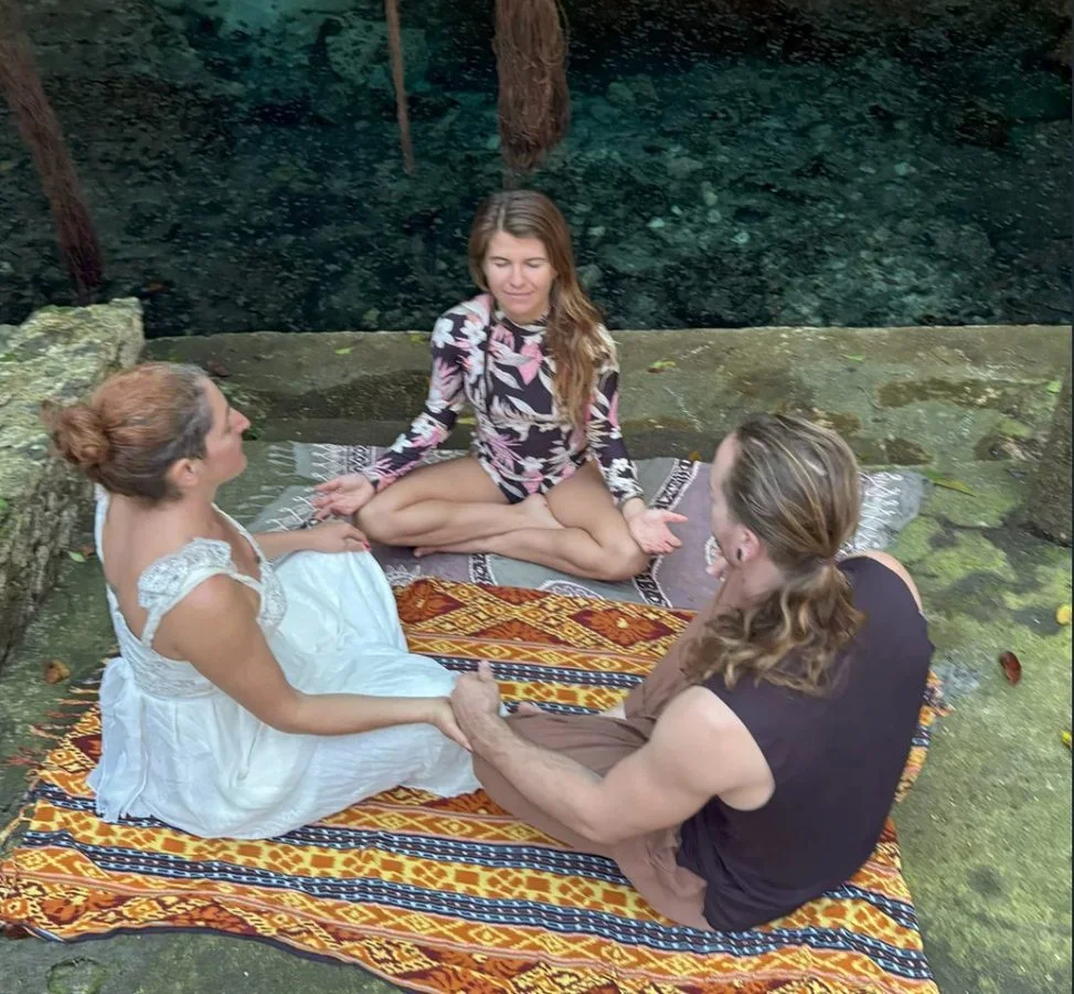 Three people sitting together by a cenote