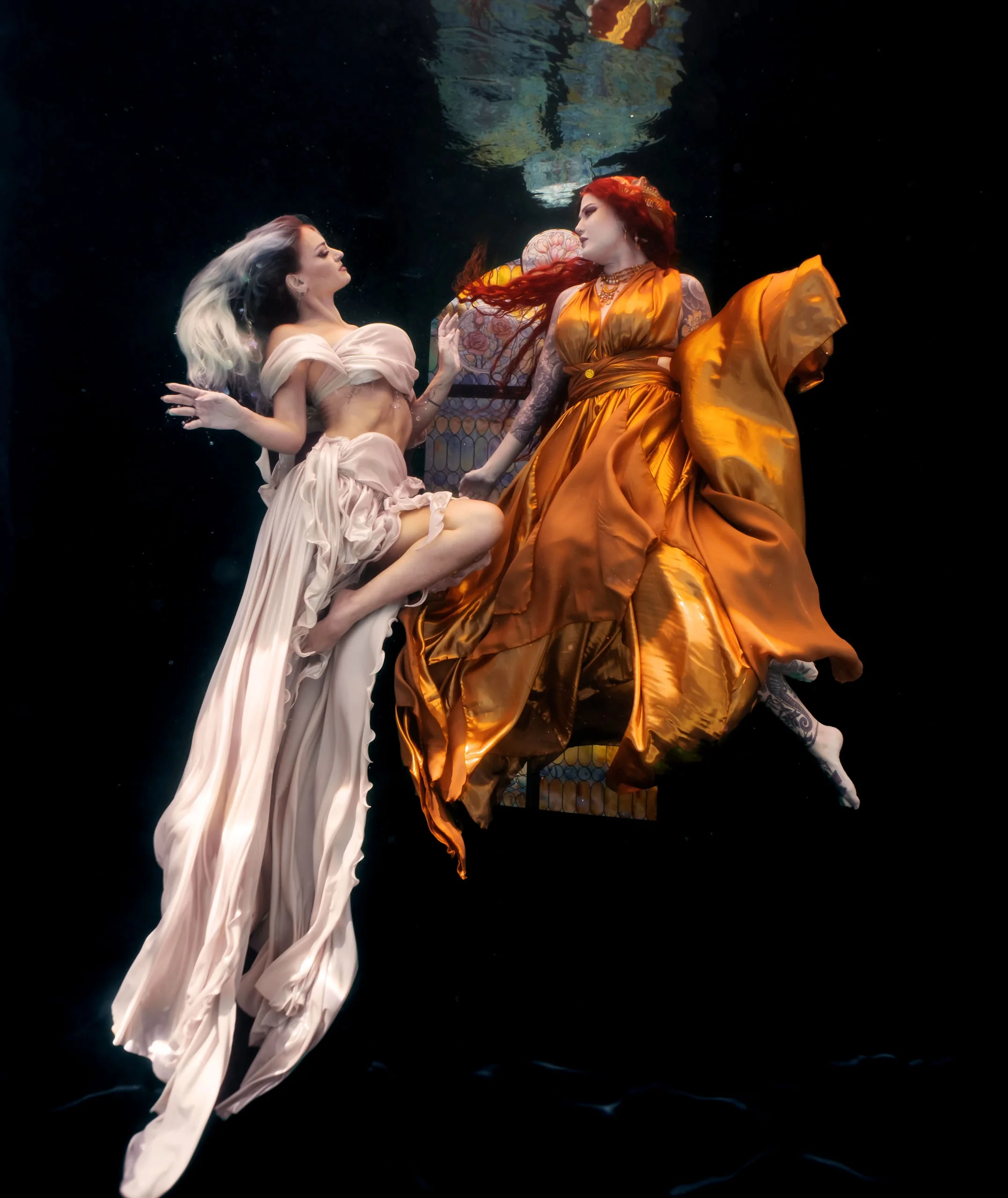 Two figures in flowing gowns meeting in dark water